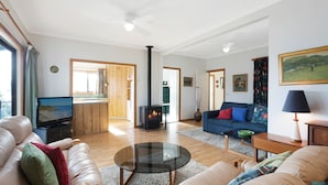 Un salón amplio con sofá, una mesa de centro de cristal, chimenea y televisión.