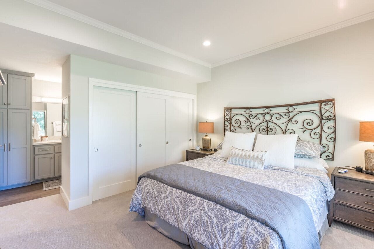 A bedroom with a large bed, a nightstand, a dresser, and a wardrobe.