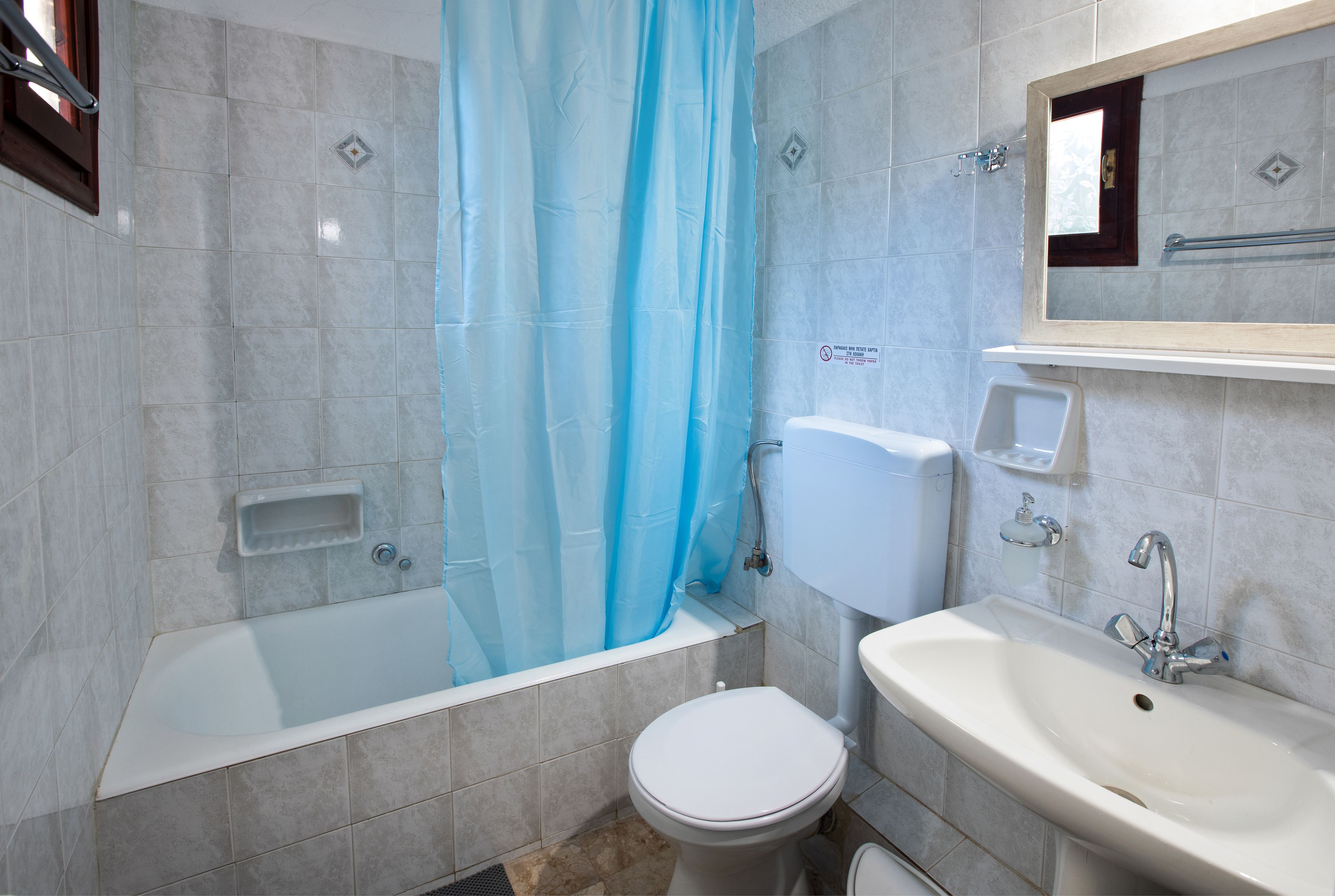 Un baño con bañera, inodoro, lavamanos y cortina de ducha.