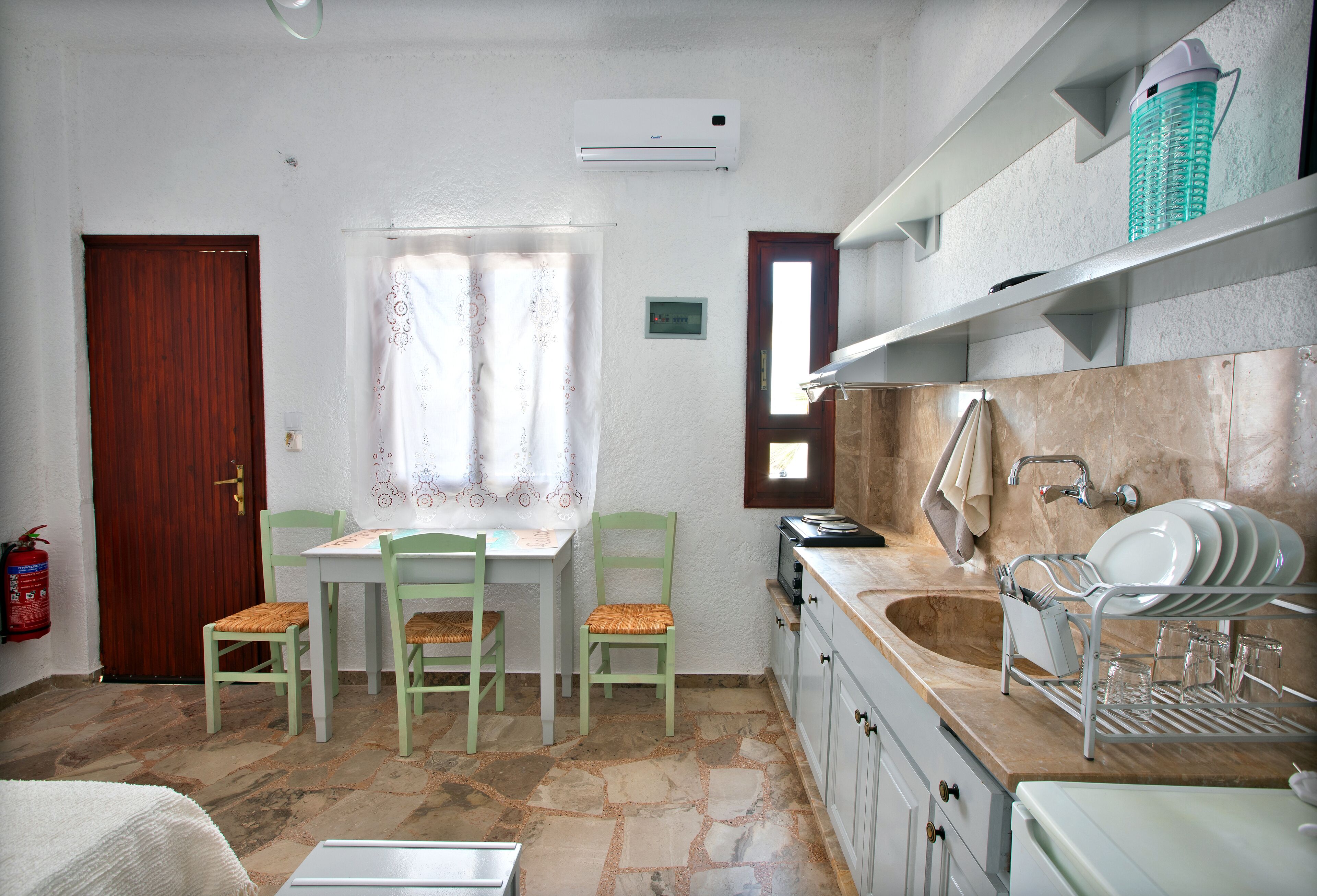 Una cocina compacta con comedor, una puerta de madera y un extintor.