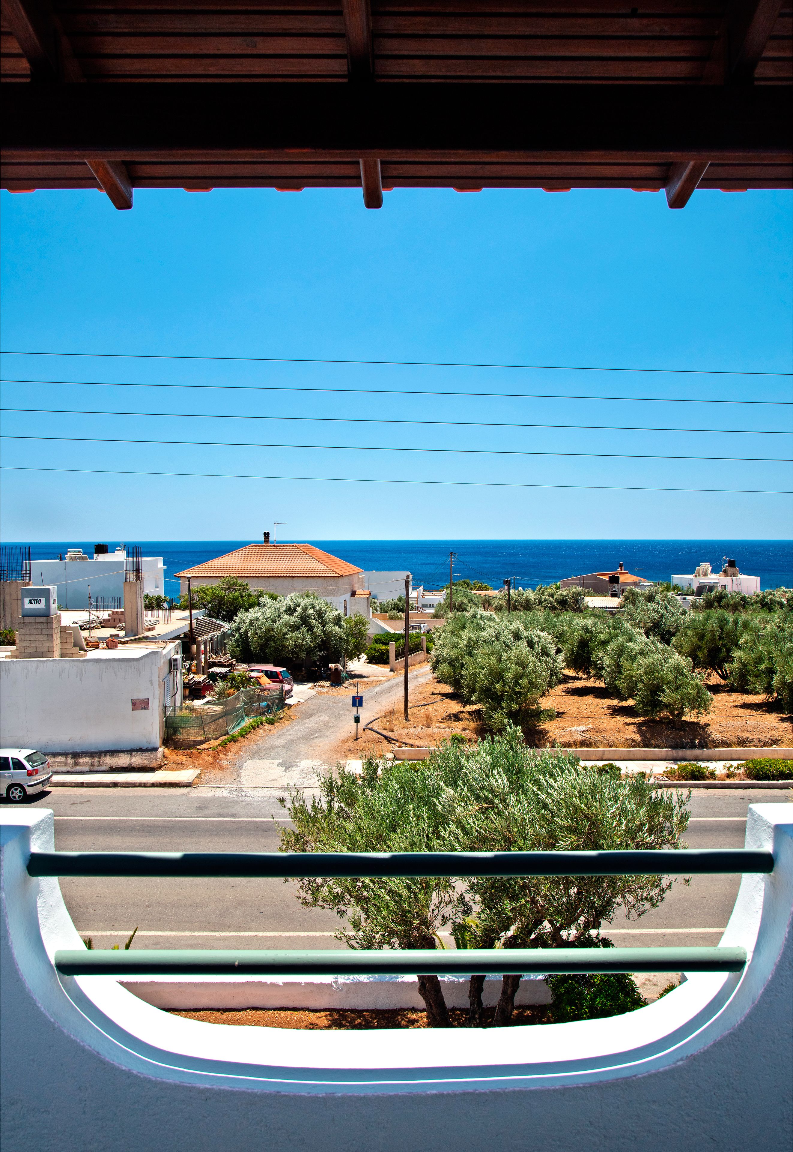 A view from a window overlooking a coastal area with buildings, trees, and a clear blue sky.