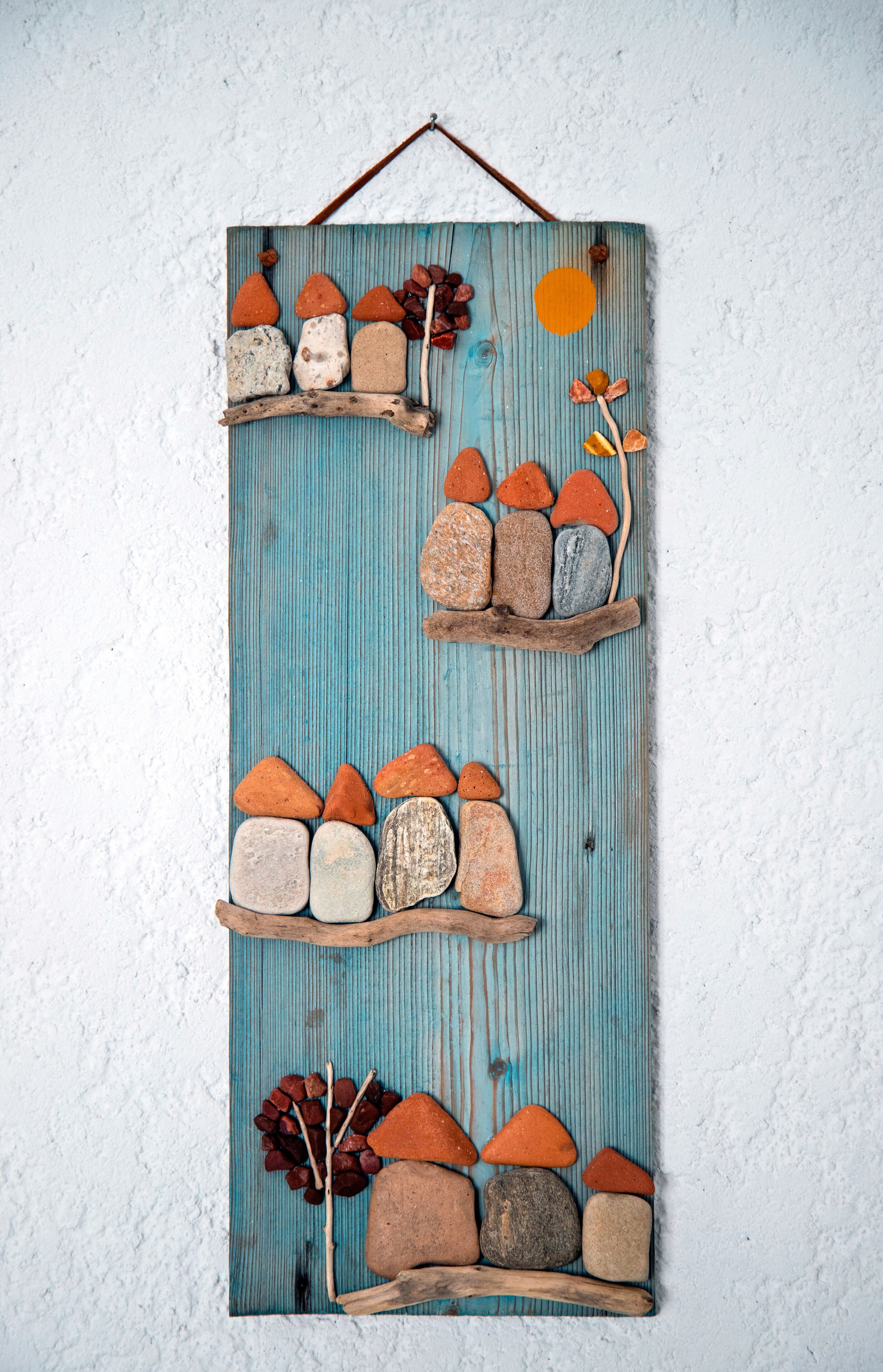 Una pieza decorativa montada en la pared con varias piedras y ramas dispuestas en una estructura escalonada, similar a un estante.