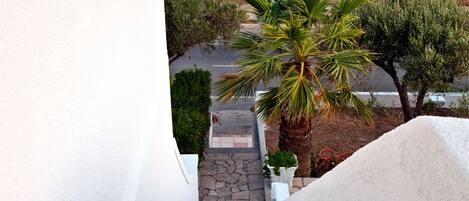 Una escalera lleva a un balcón con vista a una zona costera con casas y vegetación.