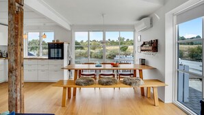 Una cocina moderna con un amplio ventanal, una mesa de madera y sillas.