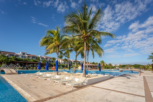 Relax by the resort pool surrounded by palm trees and lounge chairs.