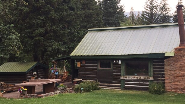 A rustic cabin with a metal roof, labeled 'HARDSCRABBLE CABIN'.