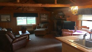 A cozy cabin interior with a living room, dining area, and kitchen.