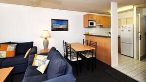 A compact living space with a sofa, a dining table, and a kitchenette. - Providence 3 - 100m to the Beach, Ground Floor Retreat (Hawks Nest)