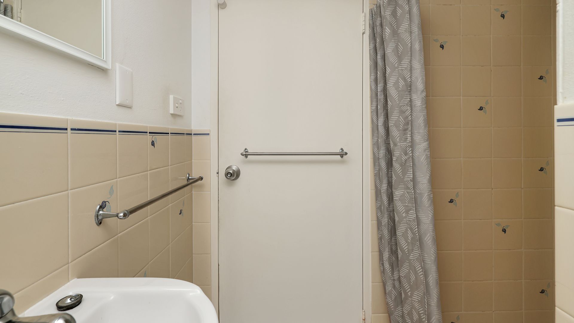 Un baño con una puerta blanca, toallero, cortina de ducha y bañera.