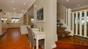A spacious kitchen with a dining area, a staircase, and a view of the outdoors. - Patch of Paradise - Iluka (Tea Gardens)