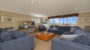 A living room with a sofa set, a coffee table, and a TV on a stand. - Patch of Paradise - Iluka (Tea Gardens)