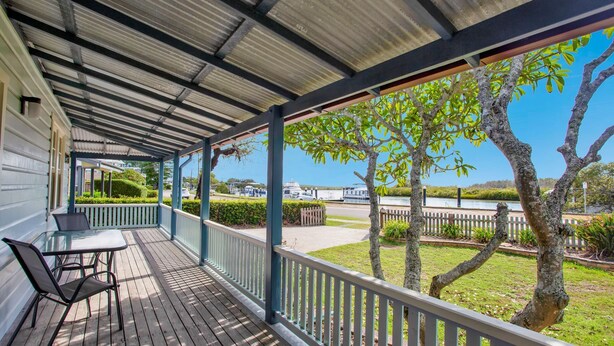 A covered porch with a table and chairs, a view of a river, and trees.