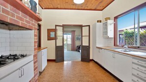 A kitchen with a brick stove, white cabinets, and a wooden ceiling.