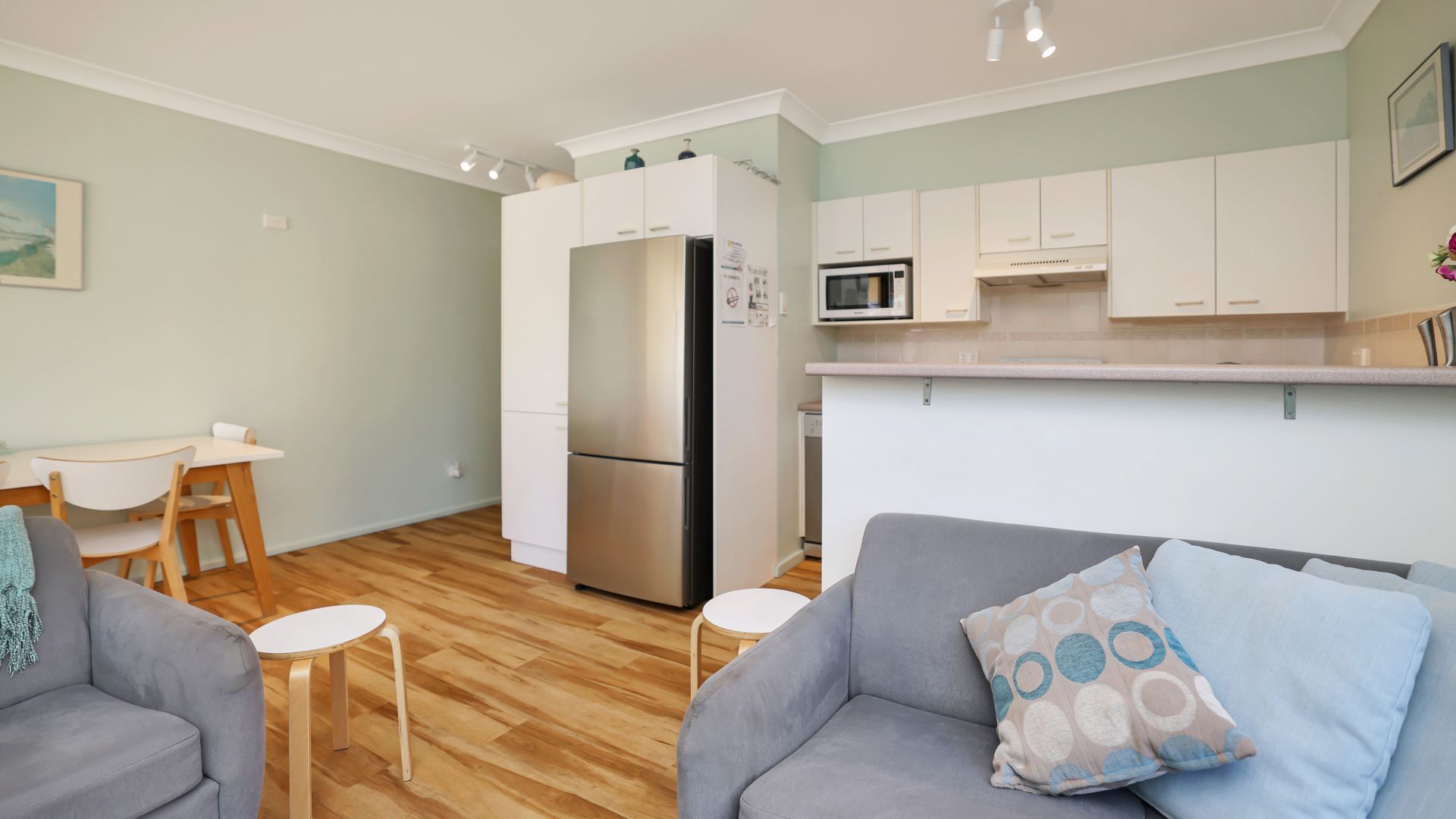 A compact living space with a kitchenette, a dining area, and a seating area with a sofa and two chairs.