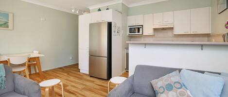 A compact living space with a kitchenette, a dining area, and a seating area with a sofa and two chairs.