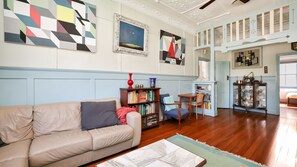 A living room with a beige sofa, a bookshelf, and a painting on the wall. - Where the River Runs (Tea Gardens)