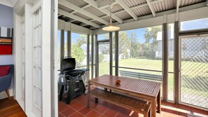 A patio area with a grill, a wooden table, and a bench. - Where the River Runs (Tea Gardens)
