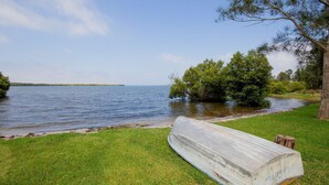 Une zone herbeuse avec une jetée en bois qui s’avance dans un lac, le tout étant entouré d’arbres.