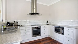 Une cuisine moderne avec des meubles blancs, des appareils en acier inoxydable et un plan de travail en granit.