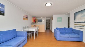 A compact living space with a dining area, kitchenette, and a view of the sea.