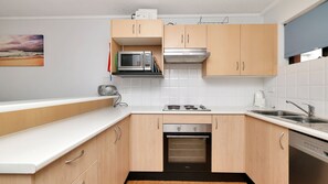 Una cocina moderna con armarios de madera, un microondas integrado, una estufa y un lavavajillas.