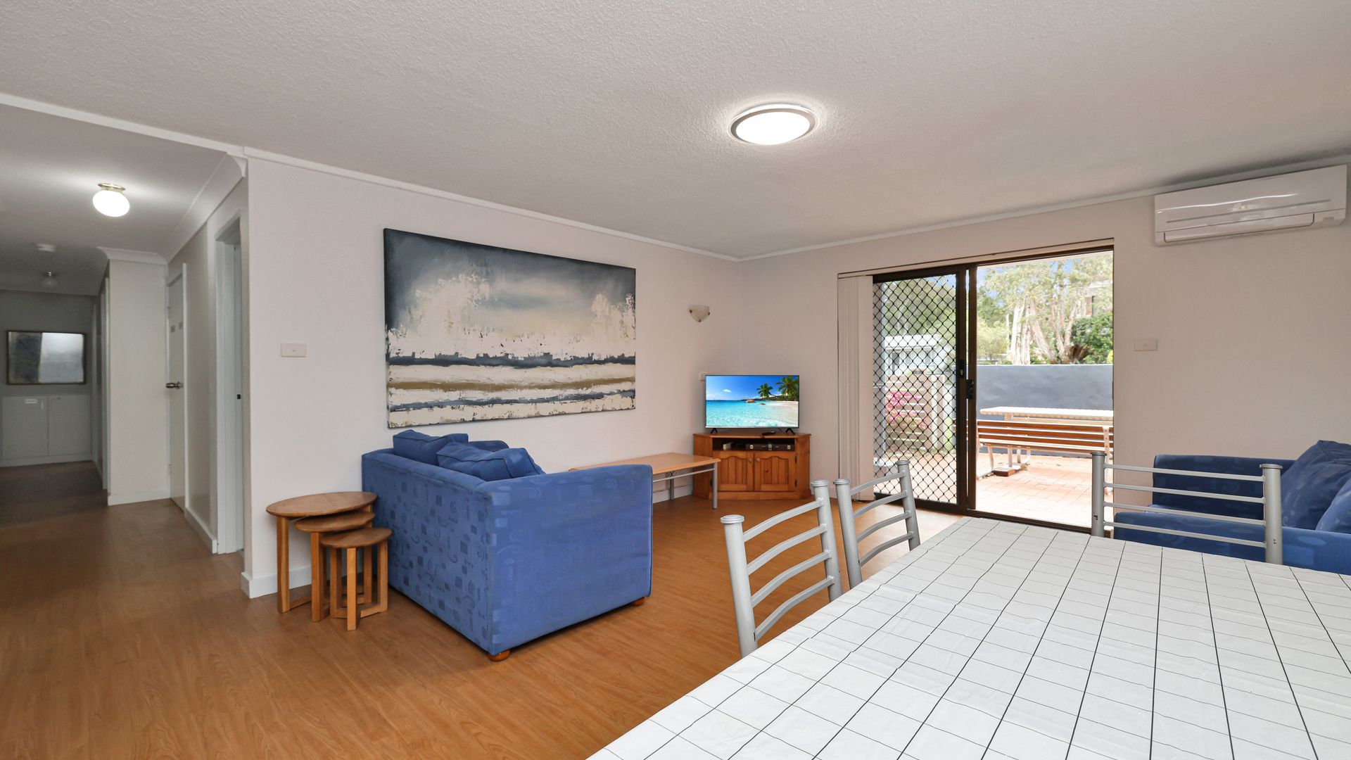 A modern living room with a sofa, a TV, and a dining area with a table.