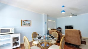 Un espacio habitable compacto con comedor, microondas, televisión y sofá.