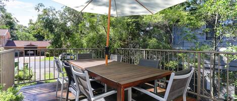 A wooden deck with a table and chairs, an umbrella, and a railing.