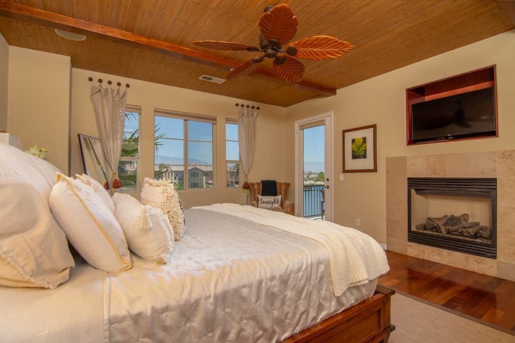 Ein Schlafzimmer mit Bett, Deckenventilator, Kamin und Blick ins Freie.