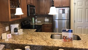 A kitchen with granite countertops, wooden cabinets, stainless steel appliances, and pendant lighting. - Westgate Resort/luxury condo experience - 3 Bedroom Lock-off - Sleeps 12 (Kissimmee)