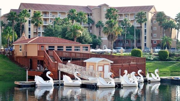 A hotel with a waterway, swan-shaped boats, and a small building with stairs leading to a dock. - Westgate Resort/luxury condo experience - 3 Bedroom Lock-off - Sleeps 12 (Kissimmee)