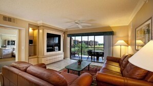 A spacious living room with leather sofas, a coffee table, and a balcony with a view of buildings. - Westgate Resort/luxury condo experience - 3 Bedroom Lock-off - Sleeps 12 (Kissimmee)