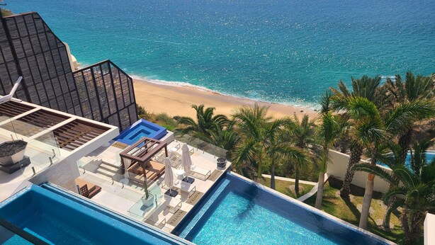 A pool area with a view of the beach and ocean.
