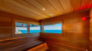 A wooden sauna with benches and a view of the ocean.