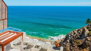A seaside terrace with lounge chairs and a view of the ocean.