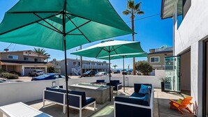 A patio area with outdoor seating, umbrellas, and a view of the ocean. - Private Patio, Steps to the Sand! Walk to Village! A/C (Carlsbad)