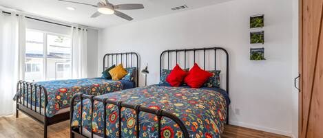 Una camera da letto con due letti, un ventilatore a soffitto e vista sull'esterno.