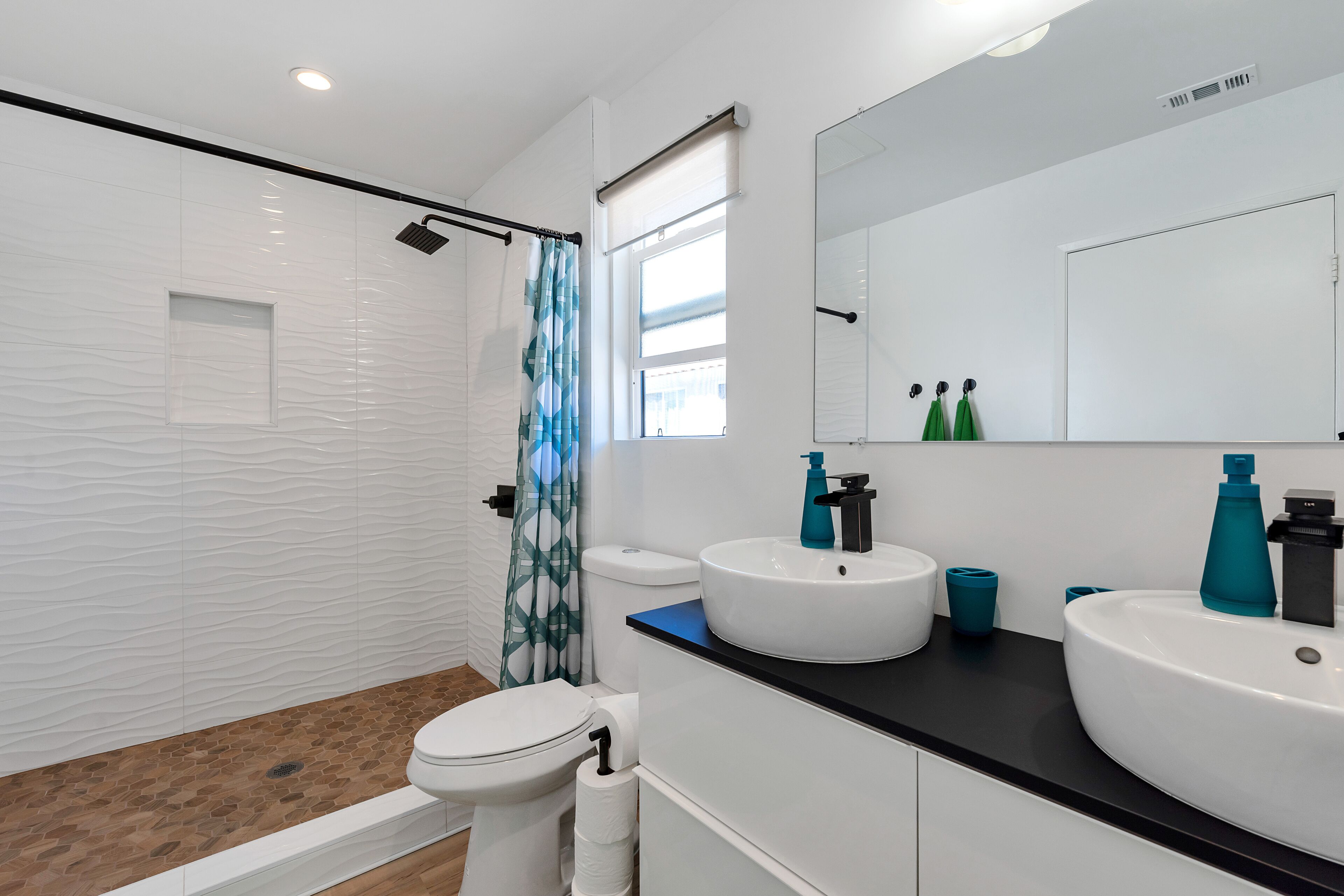 A modern bathroom with a shower, toilet, and two sinks with faucets.