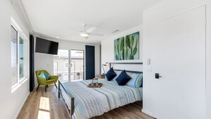 A bedroom with a bed, a chair, a ceiling fan, a TV, and a cactus painting. - Private Patio, Steps to the Sand! Walk to Village! A/C (Carlsbad)