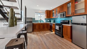 A modern kitchen with wooden cabinets, stainless steel appliances, and a blue backsplash. - Private Patio, Steps to the Sand! Walk to Village! A/C (Carlsbad)