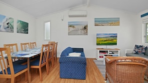 Ein Essbereich mit einem Tisch für vier Personen, Holzstühlen und einem blauen Sofa.