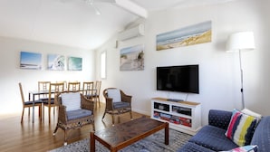 Ein Wohnzimmer mit Fernseher, Esstisch, Stühlen und einer Couch.