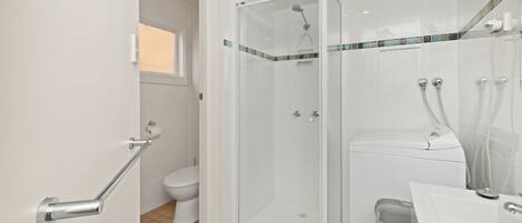 Een moderne badkamer met een douchecabine van glas, een toilet en een wastafel.