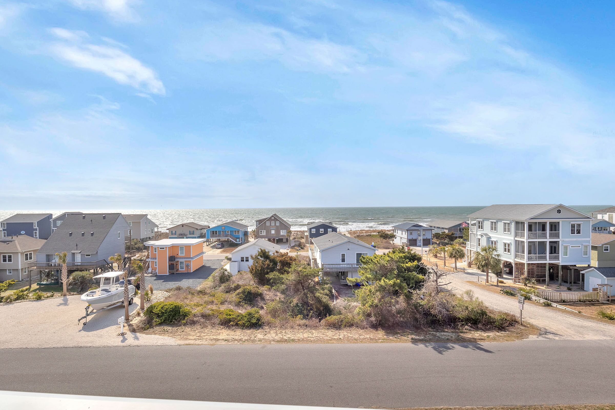A coastal residential area with houses, a beach, and a clear sky.