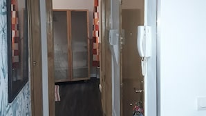 A narrow hallway with a wooden door on the right, a white wall, and a ceiling light fixture. - IN THE HEART OF GRANADA - WIFI (Granada)