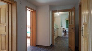 Un couloir avec des portes en bois, un coin cuisine avec une table à manger et une fenêtre bien visible.
