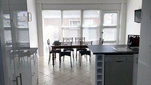 Keittiössä on ruokapöytä, tuoleja ja astianpesukone.