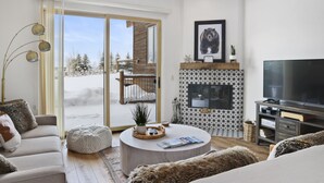 Una sala moderna con chimenea, televisor grande y un área de estar acogedora.