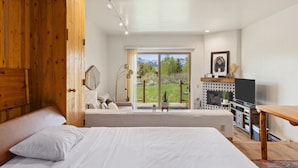Un dormitorio con una cama grande, un armario de madera, un televisor y un balcón con vistas a las montañas.