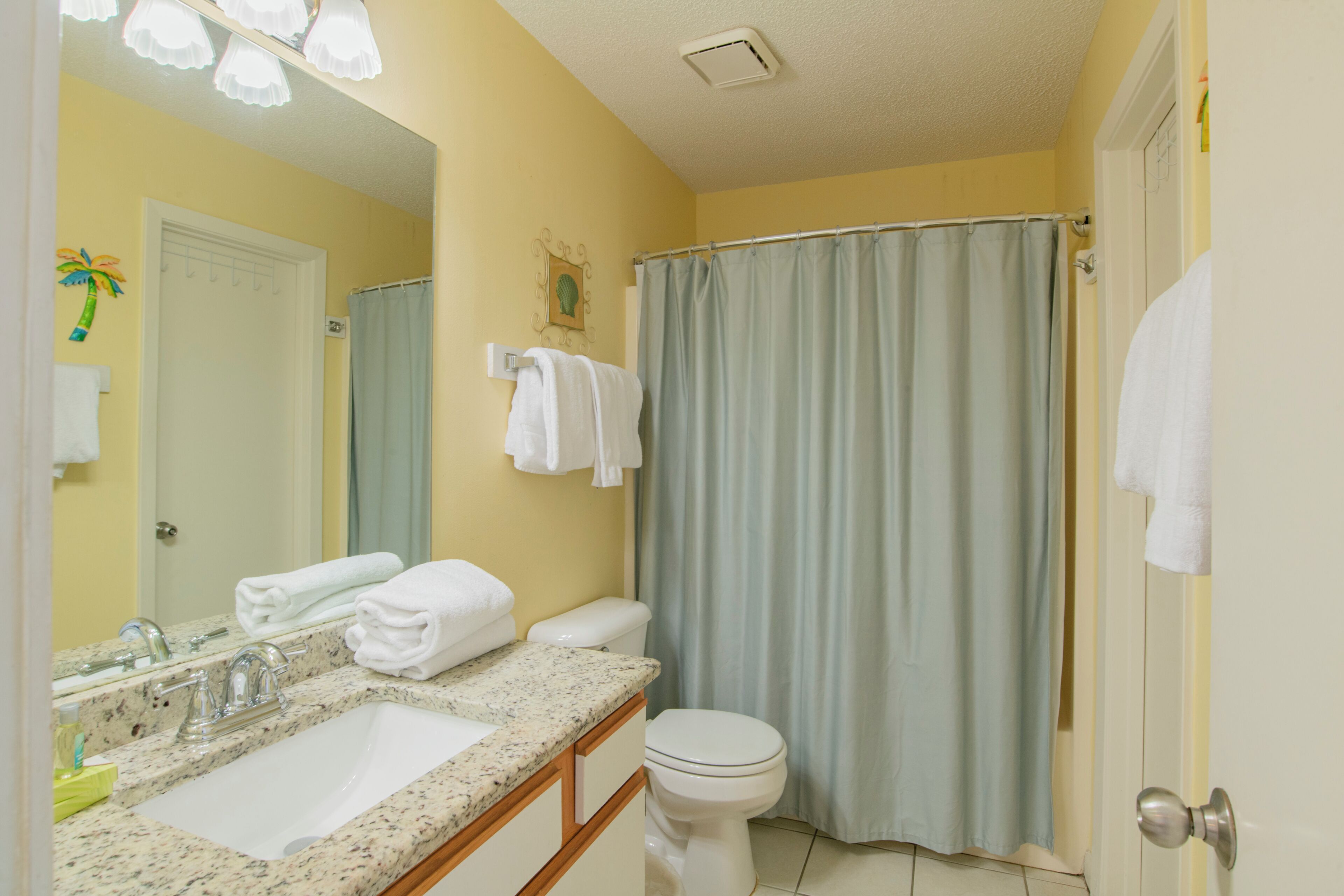 A bathroom with a sink, mirror, toilet, and shower curtain.
